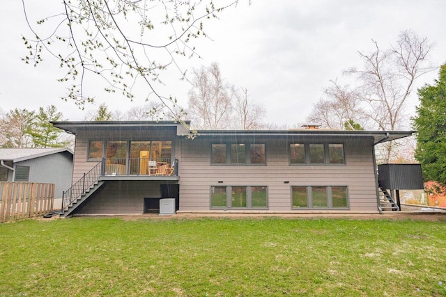 rear view of property with fence, a yard, and stairs