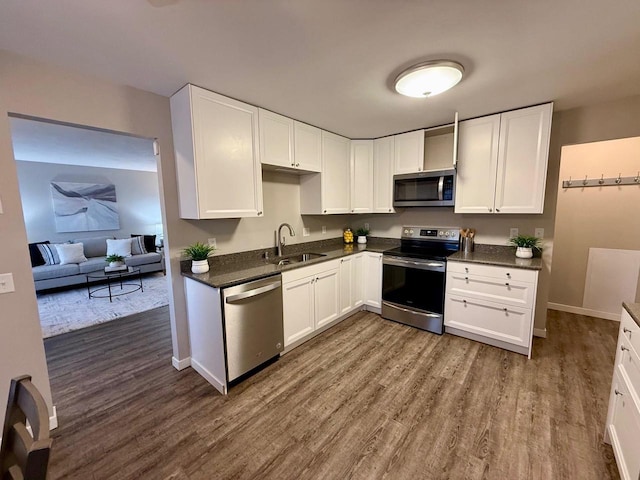 kitchen featuring a sink, dark countertops, dark wood-style floors, white cabinetry, and appliances with stainless steel finishes