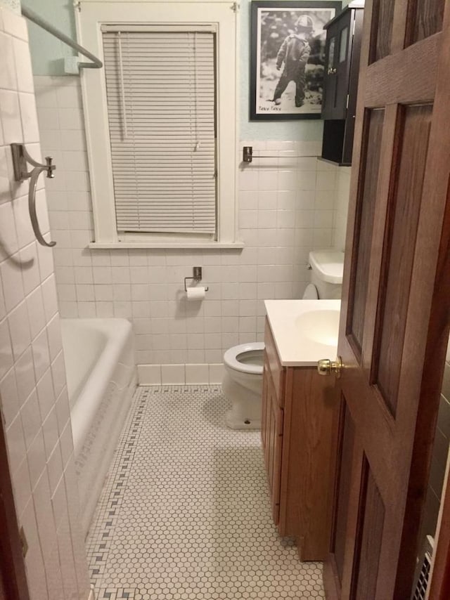 full bathroom featuring toilet, tile patterned floors, tile walls, and vanity