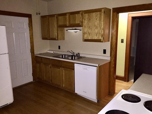 kitchen with brown cabinets, white appliances, light countertops, and a sink