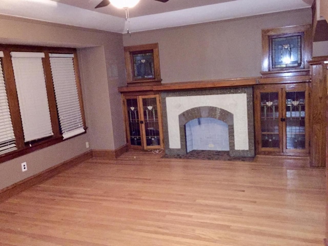 unfurnished living room with light wood-style floors, baseboards, and a ceiling fan