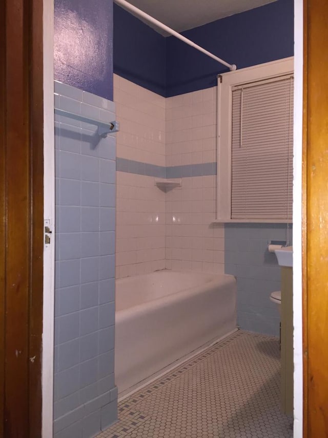 full bath featuring shower / bathtub combination, toilet, tile walls, and tile patterned floors