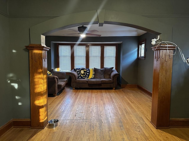 living area with a ceiling fan, arched walkways, baseboards, and wood finished floors