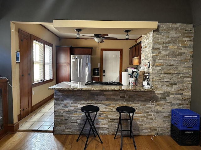 interior space featuring a peninsula, light wood-style flooring, appliances with stainless steel finishes, and a breakfast bar