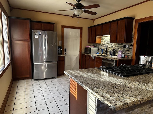 kitchen featuring decorative backsplash, light stone countertops, crown molding, black appliances, and a sink