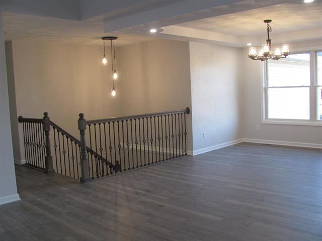 unfurnished room with dark wood-style floors, a chandelier, a raised ceiling, and baseboards