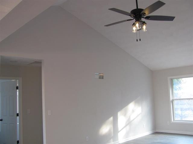 spare room with light wood finished floors, baseboards, vaulted ceiling, and a ceiling fan