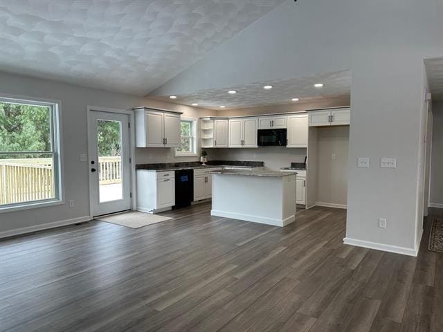 kitchen with dark wood-style flooring, a kitchen island, white cabinets, black appliances, and dark countertops