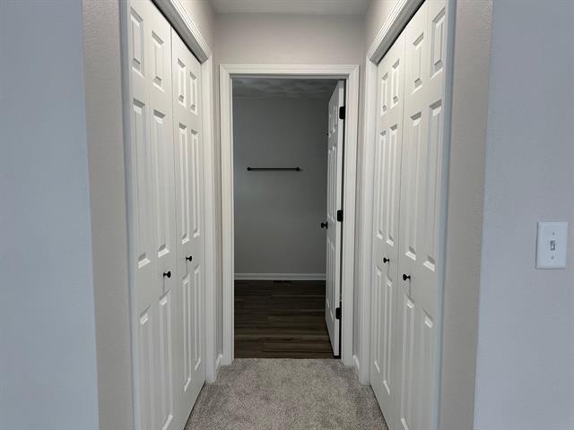 hallway featuring light carpet and baseboards