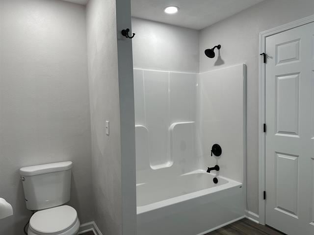 bathroom featuring washtub / shower combination, toilet, and wood finished floors