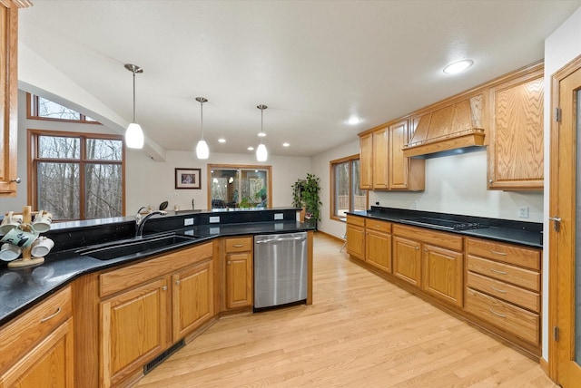 kitchen with dark countertops, visible vents, stainless steel dishwasher, a sink, and premium range hood