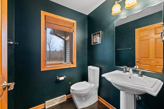 half bathroom with baseboards, visible vents, toilet, tile patterned flooring, and a sink