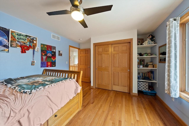 bedroom with light wood finished floors, a closet, visible vents, a ceiling fan, and baseboards