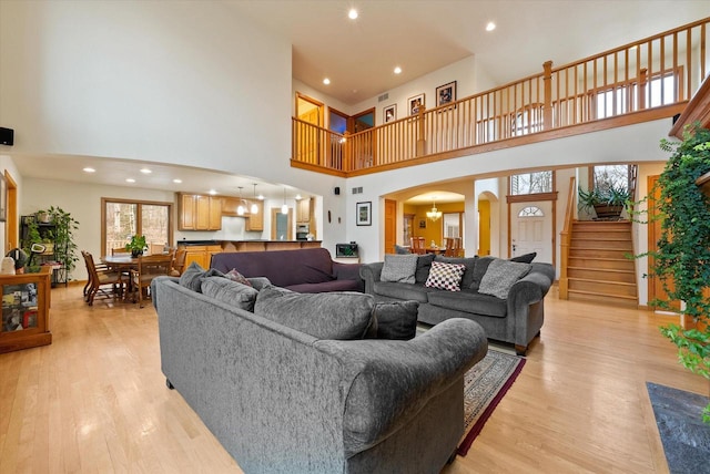 living area featuring light wood-style floors, stairs, arched walkways, and recessed lighting