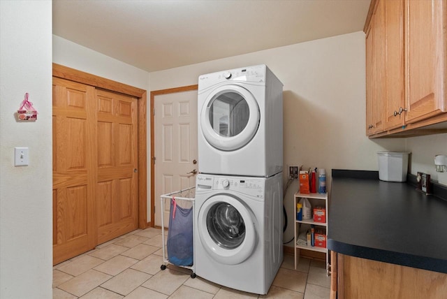 laundry room featuring stacked washer / drying machine, cabinet space, and light tile patterned flooring