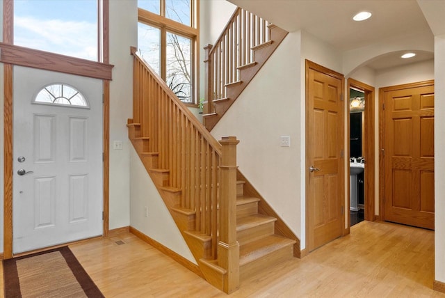 foyer with arched walkways, a healthy amount of sunlight, and wood finished floors