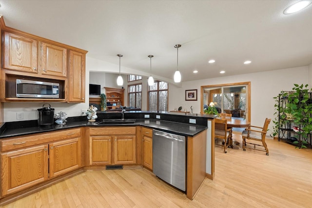 kitchen featuring light wood-style flooring, a peninsula, hanging light fixtures, stainless steel appliances, and a sink