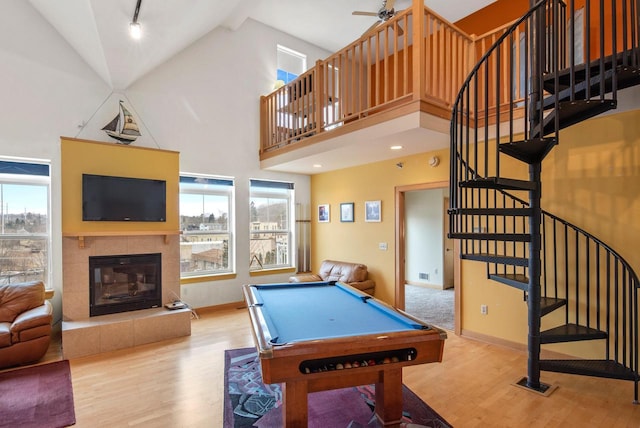 recreation room featuring a tiled fireplace, wood finished floors, and a healthy amount of sunlight