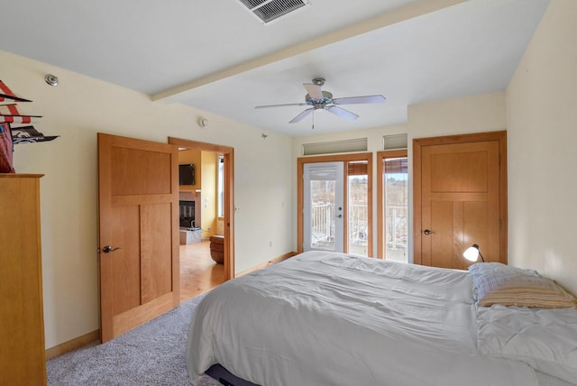 bedroom featuring visible vents, baseboards, access to exterior, beam ceiling, and a glass covered fireplace