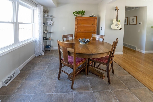 dining space with dark wood-style floors, visible vents, and baseboards