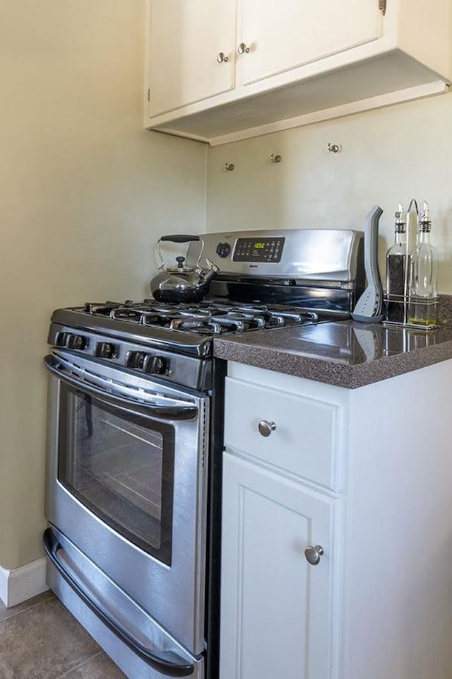 kitchen featuring stainless steel range with gas cooktop, white cabinetry, and dark countertops