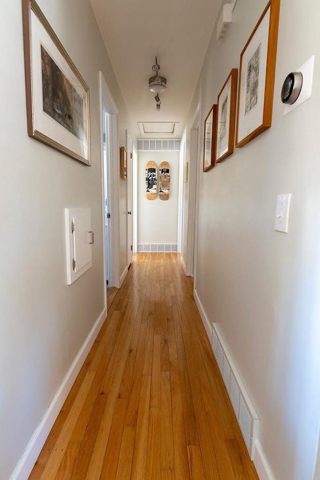 corridor with light wood-type flooring, baseboards, and visible vents