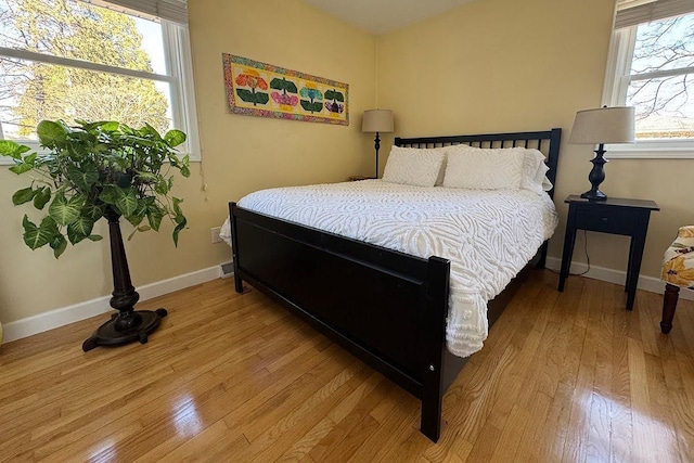 bedroom with multiple windows, baseboards, and hardwood / wood-style flooring