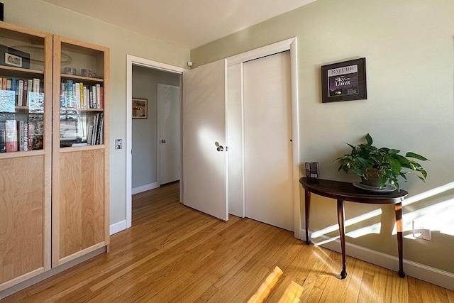 corridor with baseboards and light wood-style floors