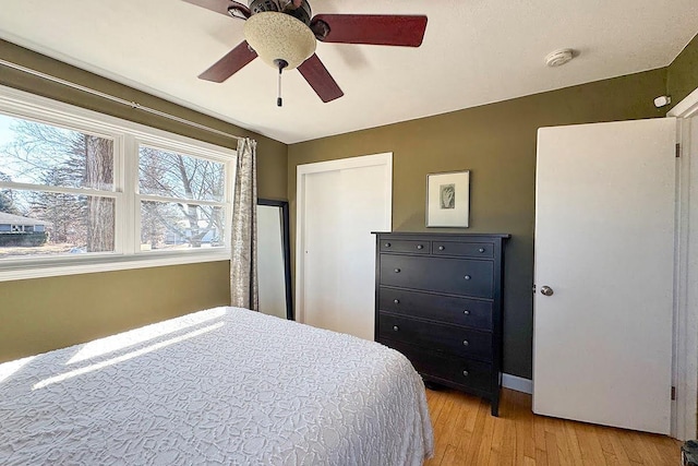 bedroom featuring ceiling fan, a closet, light wood-type flooring, and baseboards