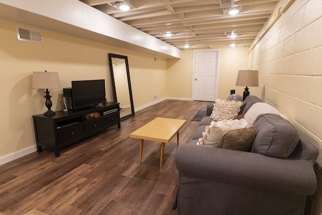 living room featuring dark wood-type flooring, concrete block wall, visible vents, and baseboards