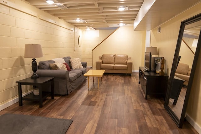 living room featuring visible vents, dark wood-type flooring, and concrete block wall