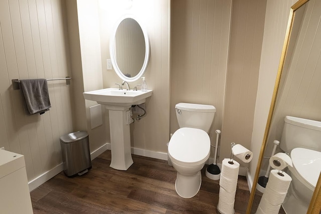 half bathroom with toilet, baseboards, and wood finished floors