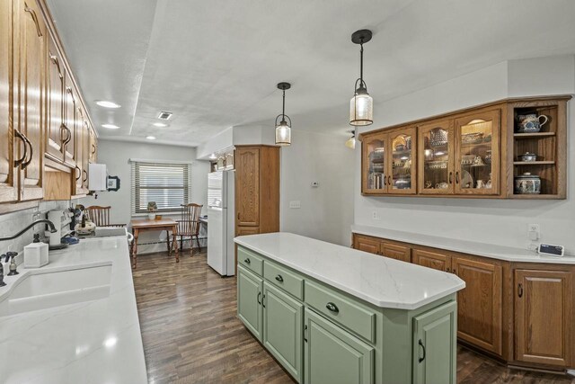 kitchen with dark wood-style flooring, a sink, a kitchen island, green cabinets, and freestanding refrigerator