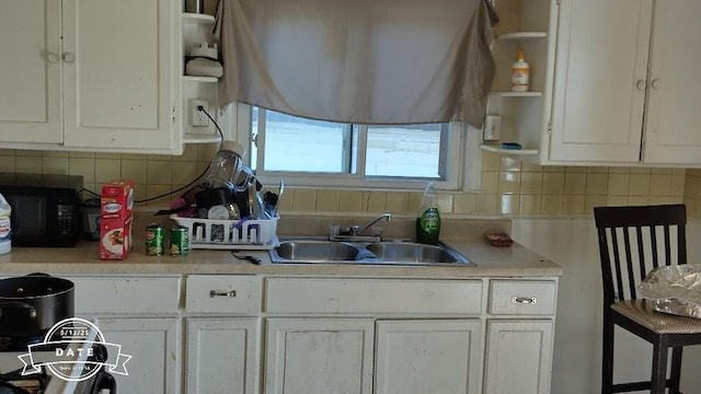 2331 S 15th St, Milwaukee, WI 53215 - kitchen with black microwave, open shelves, backsplash, white cabinets, and light countertops