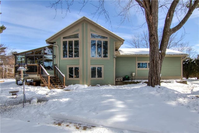 snow covered rear of property with a deck and stairway