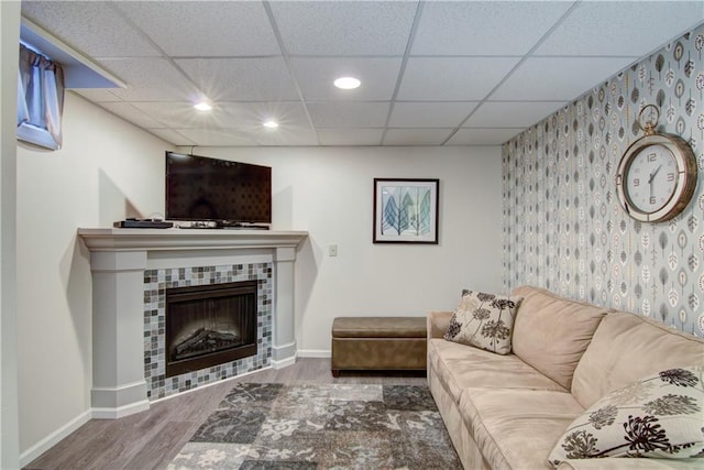 living room featuring recessed lighting, a tiled fireplace, an accent wall, wood finished floors, and baseboards