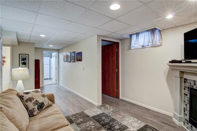 living area with recessed lighting, a tiled fireplace, wood finished floors, and baseboards