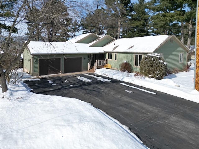 single story home featuring a garage and aphalt driveway