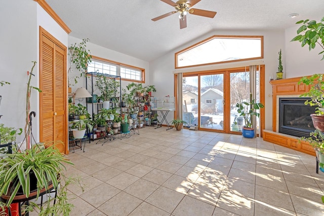 sunroom / solarium featuring a glass covered fireplace, ceiling fan, and lofted ceiling