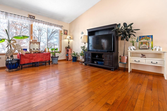 living area featuring lofted ceiling, baseboards, and hardwood / wood-style floors