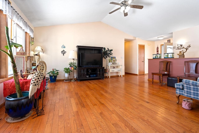 living room with vaulted ceiling, ceiling fan, wood-type flooring, and baseboards