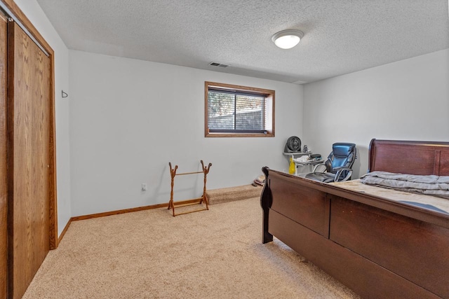 bedroom featuring light carpet, a textured ceiling, visible vents, and baseboards