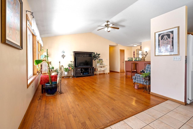 living area featuring vaulted ceiling, light wood-style flooring, baseboards, and ceiling fan