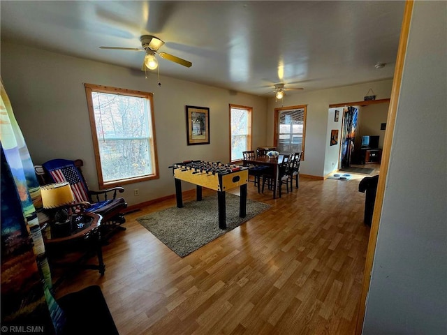 rec room featuring a ceiling fan, wood finished floors, a wealth of natural light, and baseboards