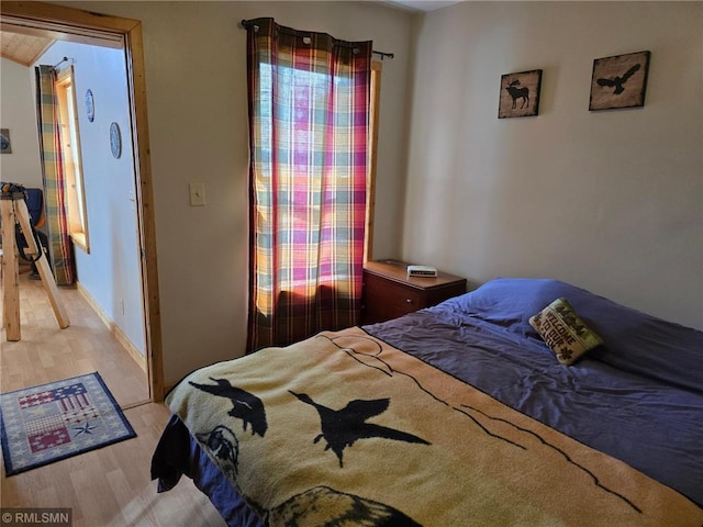 bedroom with light wood finished floors and baseboards