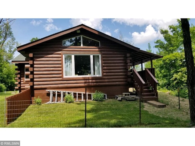 view of property exterior with stairs, log siding, and a yard