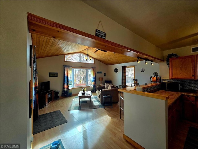 interior space featuring rail lighting, visible vents, light wood-style flooring, vaulted ceiling, and wooden ceiling