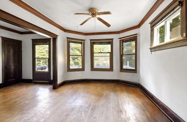 unfurnished room with wood-type flooring, baseboards, ceiling fan, and crown molding