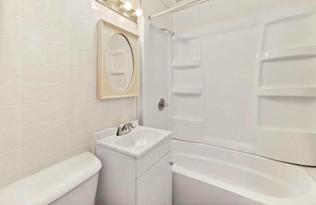 bathroom with shower / bathtub combination, toilet, vanity, and tile walls