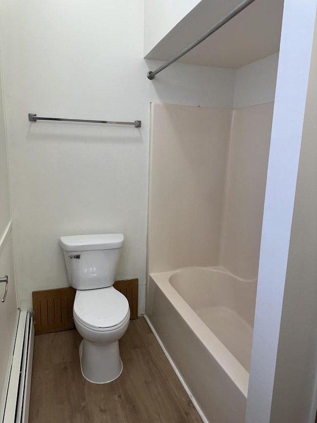 bathroom featuring a baseboard heating unit, shower / tub combination, wood finished floors, and toilet